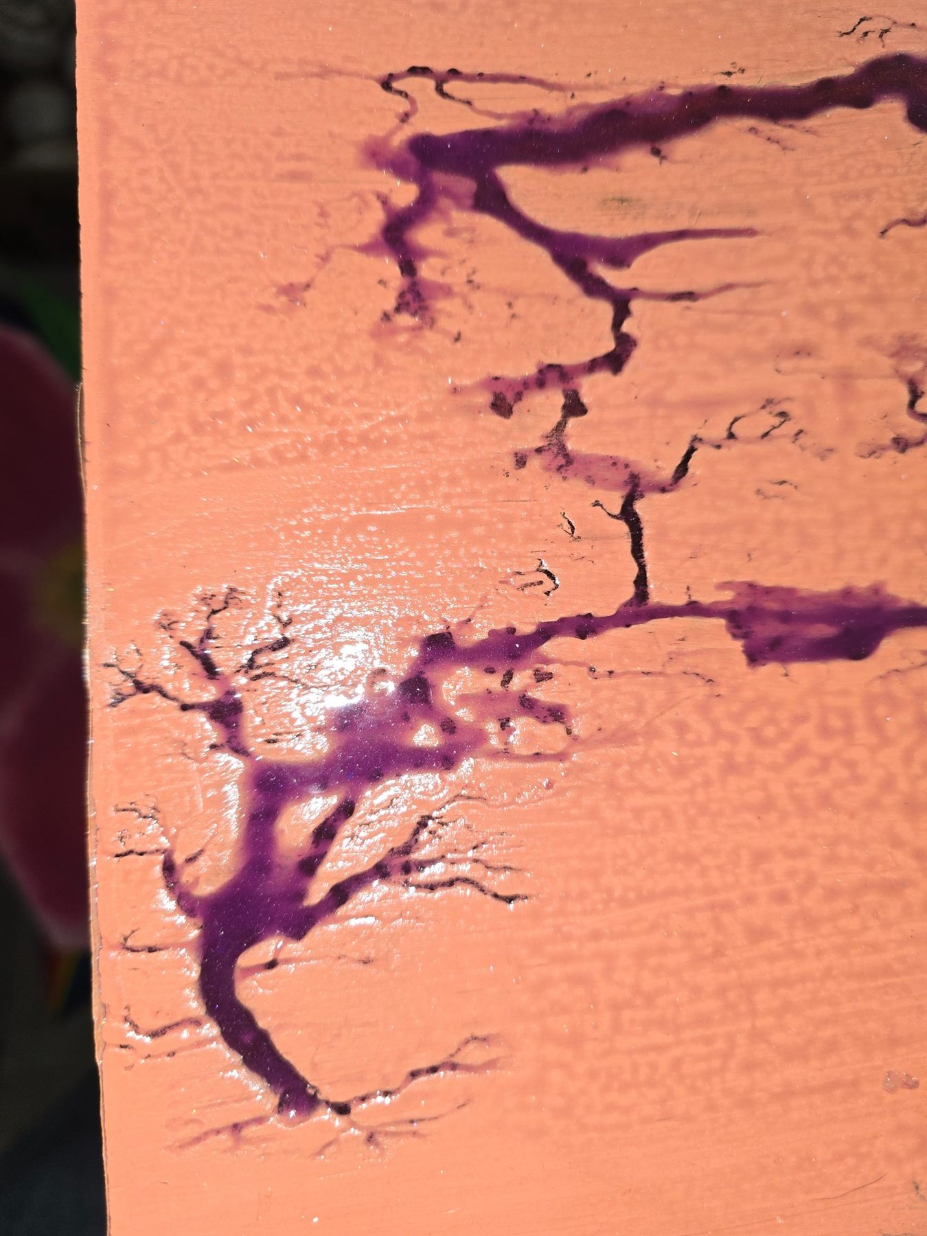 A close view of purple epoxy flowing through fractal-burned wood